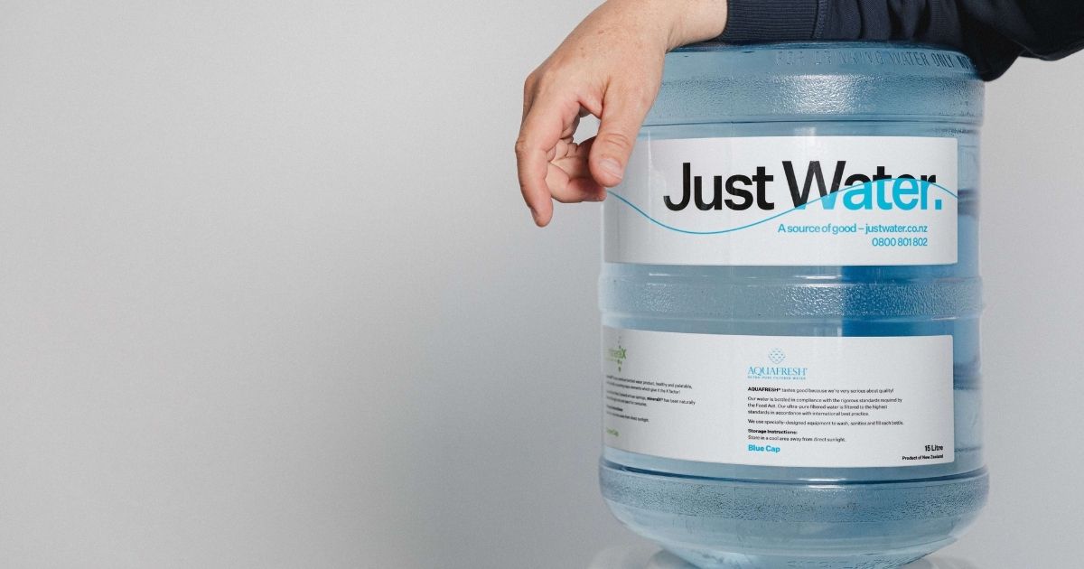 Hand leaning on a Just Water bottle