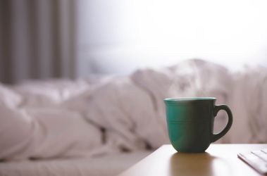 Hot cup of water in mug on side table